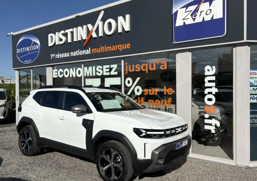 Dacia Duster 1.6 Hybrid blanc métallisé en 3/4 avant droit, avec jantes alliage noires et barres de toit noires.