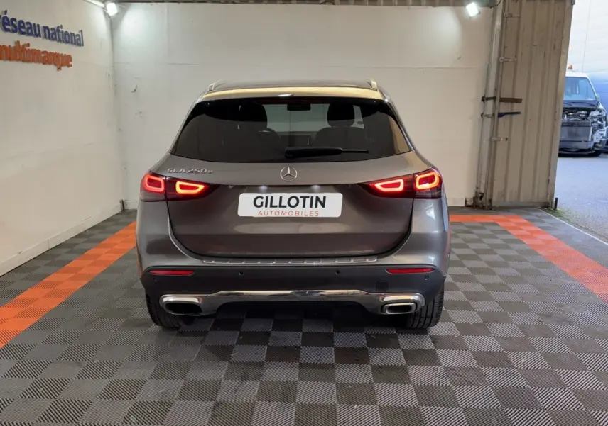 Vue arrière d'un Mercedes GLA 250 e Business Line gris foncé avec feux LED allumés en intérieur showroom.