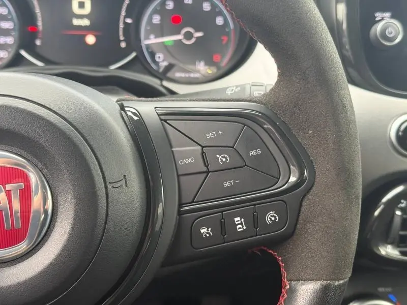 Gros plan sur le volant côté droit du Fiat 500X 2024 avec commandes de régulateur de vitesse et finition cuir noir.