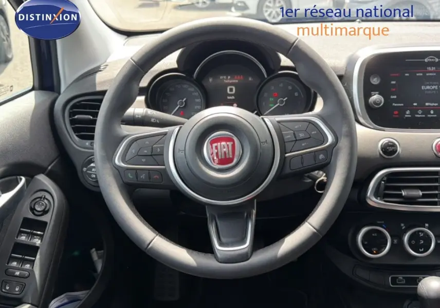 Vue intérieure centrée sur le volant du Fiat 500X 2024, avec tableau de bord et commandes visibles en noir.