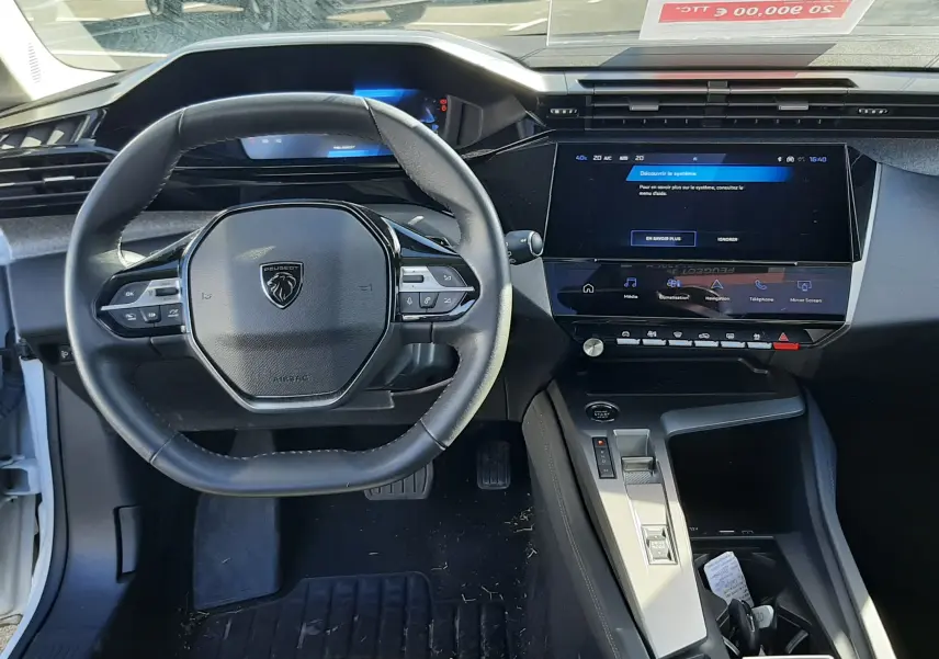 Vue intérieure centrée sur le volant et la console centrale d'une Peugeot 308 blanche 2024 avec écran tactile et commandes au volant.