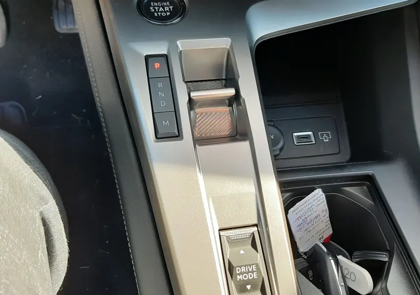 Vue rapprochée de la console centrale grise avec bouton start, sélecteur de boîte auto et commande Drive Mode de la Peugeot 308 2024.