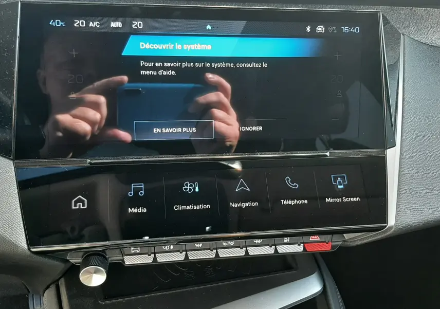 Vue rapprochée de l’écran tactile central et console de la Peugeot 308 2024 blanche, affichant le menu multimédia.