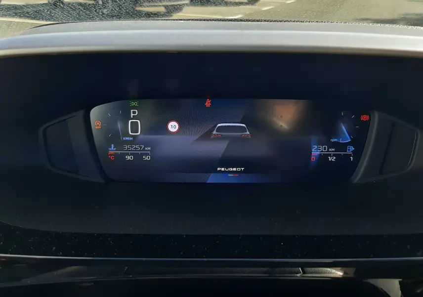 Tableau de bord numérique de Peugeot 308 2024, affichage central avec indicateurs de vitesse et autonomie, vue intérieure frontale.