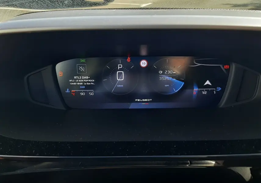 Tableau de bord numérique de Peugeot 308 blanc, affichant la vitesse à l'arrêt et le compteur kilométrique.