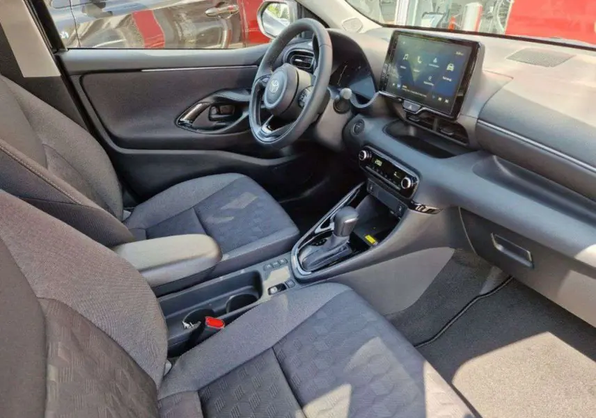 Intérieur de la Toyota Yaris 2025 gris minéral, vue côté conducteur, tableau de bord moderne avec écran tactile et boîte auto.