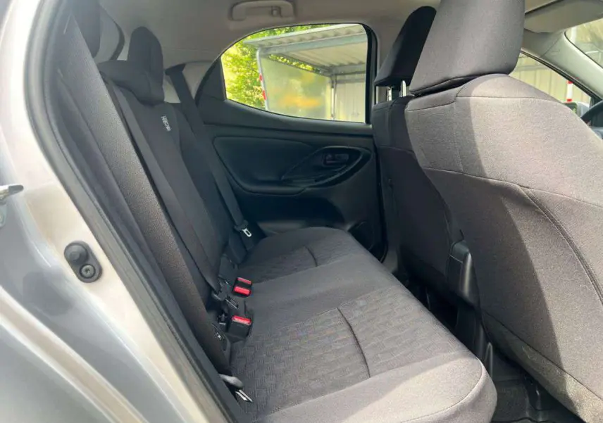 Vue intérieure côté gauche des sièges arrière en tissu gris foncé de la Toyota Yaris 1.5 Hybrid 2025 gris minéral.