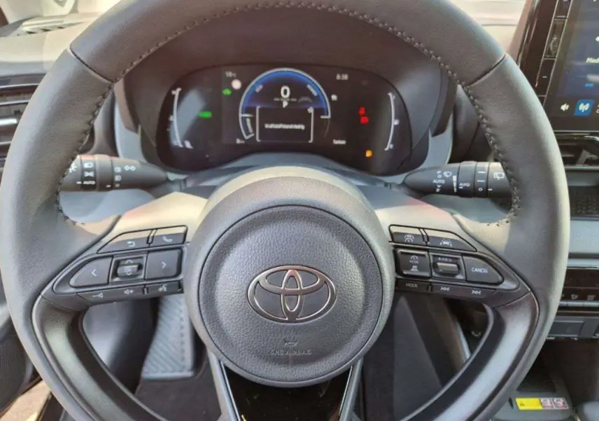 Vue rapprochée du volant noir de la Toyota Yaris 2025 hybride avec commandes intégrées et tableau de bord digital.