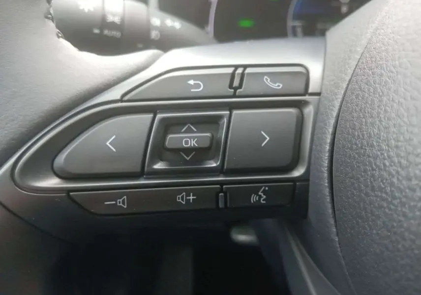 Gros plan sur les commandes au volant côté gauche de la Toyota Yaris 2025 gris minéral hybride.
