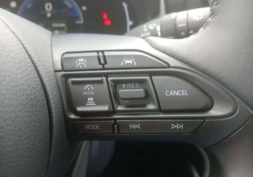 Gros plan sur les commandes au volant droit de la Toyota Yaris 2025 gris minéral, avec régulateur de vitesse et aides à la conduite.