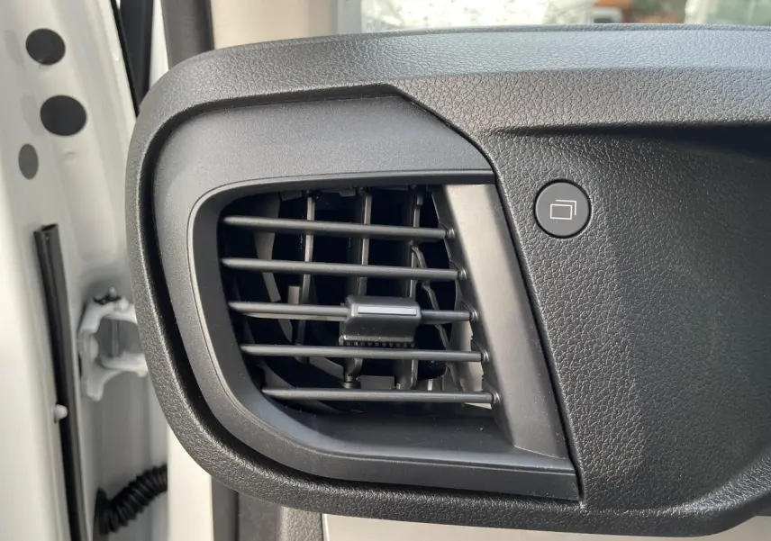 Détail de la grille d'aération noire sur le tableau de bord côté conducteur d'un Opel Vivaro blanc 2024.