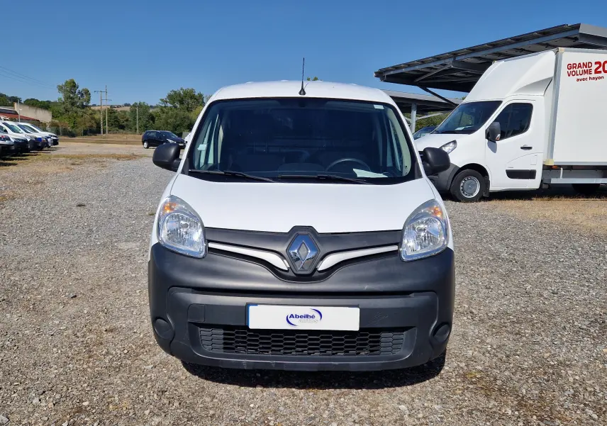 Vue avant d'un Renault Kangoo blanc 2021 avec pare-chocs noir mat sur un terrain gravillonné en extérieur.