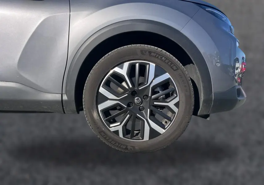 Gros plan sur la roue avant droite d'une Citroën C4 X gris mercure avec jante alu au design géométrique.