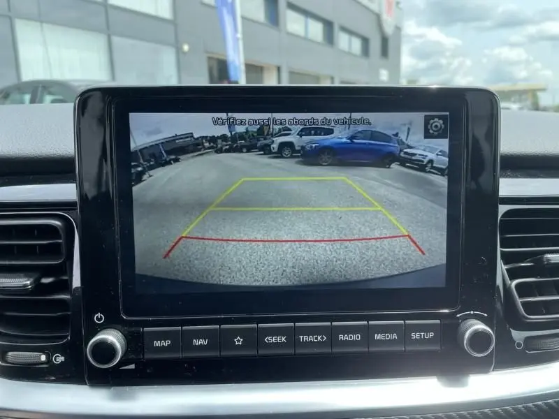 Vue arrière via caméra de recul montrant une BMW Série 1 F20 135i bleu métal garée côté droit dans un parking.