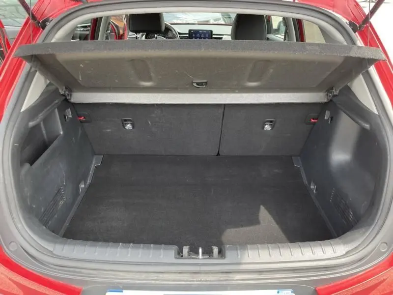 Coffre ouvert vu de l'arrière d'une BMW Série 1 F20 135i rouge, montrant l'espace de chargement et l'intérieur partiel.