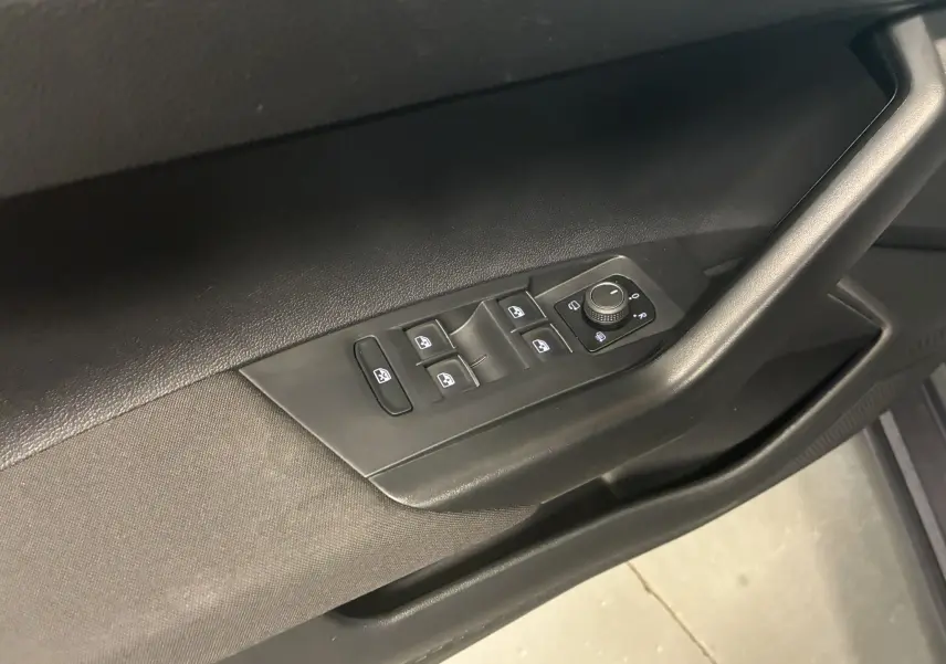 Vue rapprochée des commandes des vitres et des rétroviseurs sur la porte côté conducteur du Volkswagen Taigo gris 2023.
