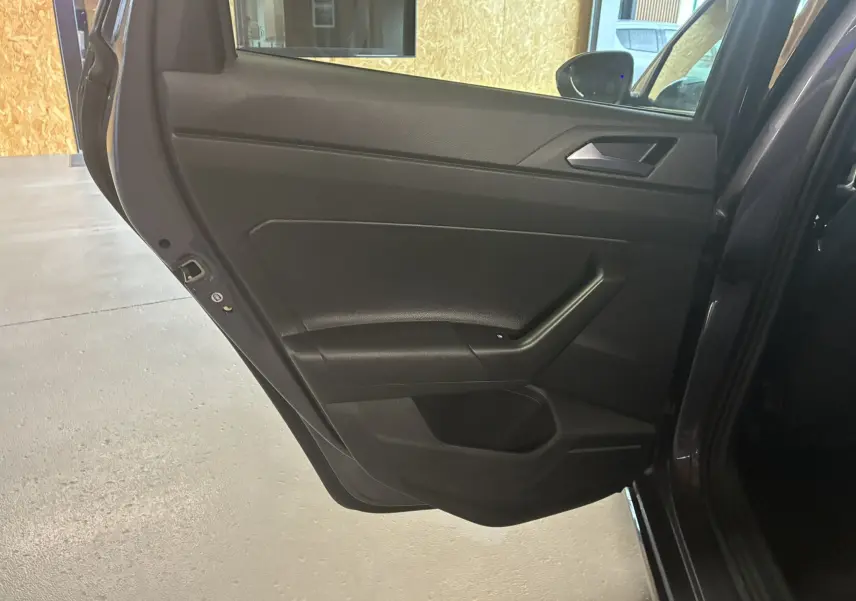 Vue rapprochée de la porte arrière gauche gris foncé du Volkswagen Taigo 2023 avec poignée intégrée et panneau épuré.