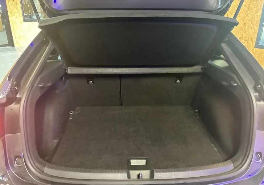 Coffre ouvert du Volkswagen Taigo gris 2023, vue arrière montrant l'espace de chargement vide et la moquette noire.