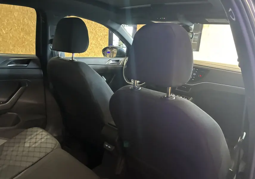 Vue intérieure arrière du Volkswagen Taigo gris 2023, mettant en valeur les sièges tissu gris-noir et le tableau de bord avant.