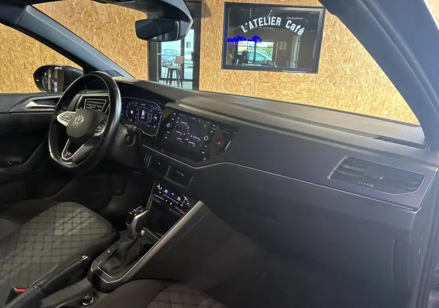 Intérieur côté conducteur du Volkswagen Taigo gris 2023, tableau de bord moderne avec écran tactile et volant multifonction.