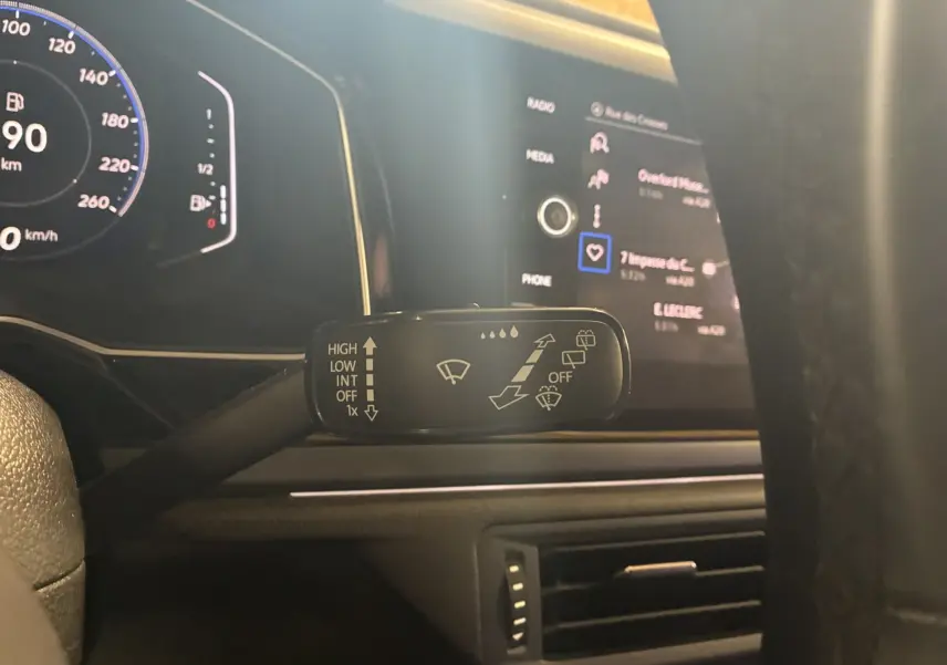 Gros plan sur la commande des essuie-glaces du Volkswagen Taigo gris, avec tableau de bord numérique et écran tactile en arrière-plan.