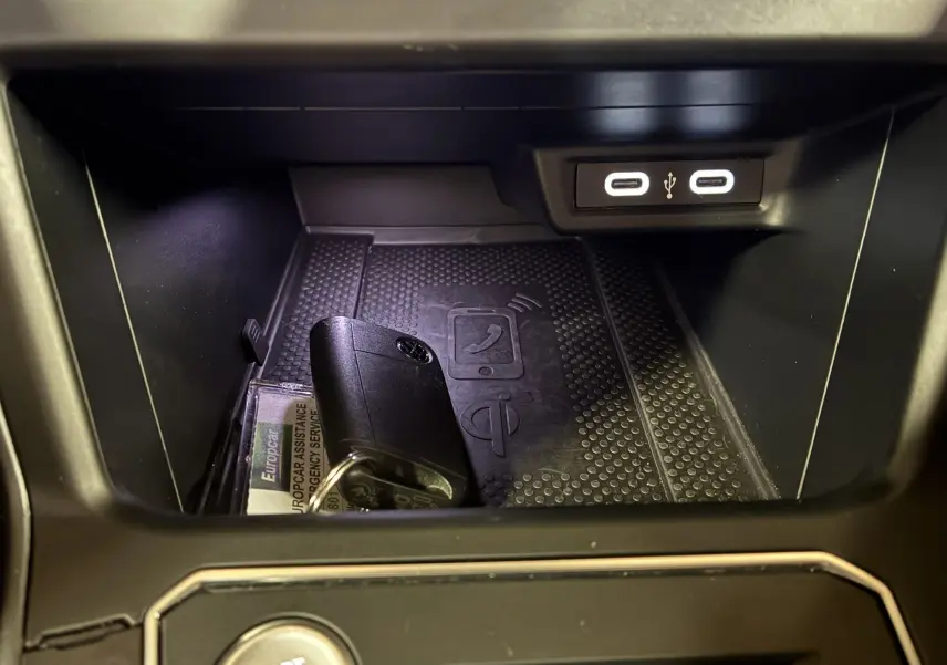 Gros plan sur la console centrale du Volkswagen Taigo gris, montrant un espace de rangement avec clé et ports USB éclairés.