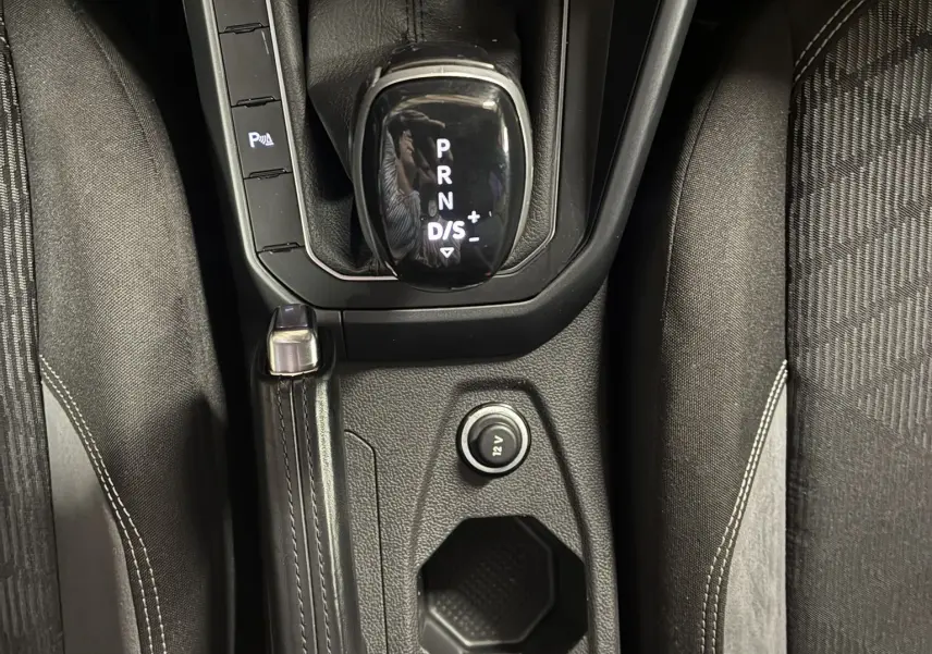 Vue plongeante sur la console centrale grise du Volkswagen Taigo 2023, montrant levier de vitesses automatique et frein à main.