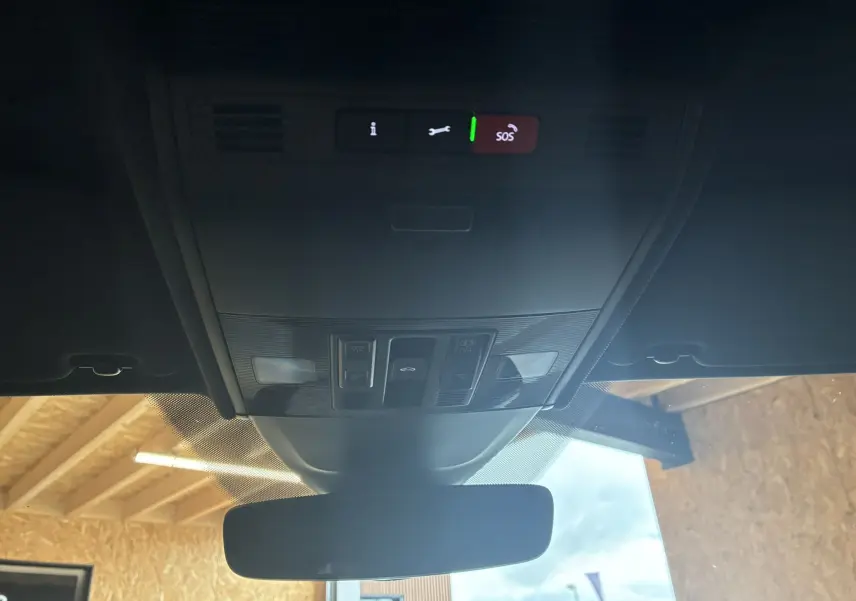 Vue intérieure du plafond avant du Volkswagen Taigo gris 2023, montrant les commandes d'éclairage et le bouton SOS au-dessus du rétroviseur.