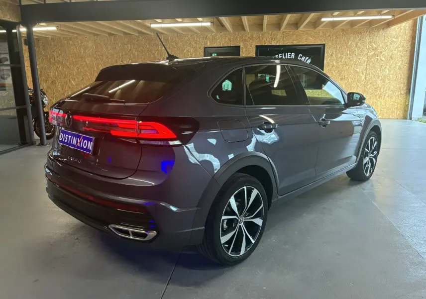 Volkswagen Taigo 1.5 TSI 150 R-LINE gris, vue 3/4 arrière droit, feux arrière allumés et jantes alliage noires.