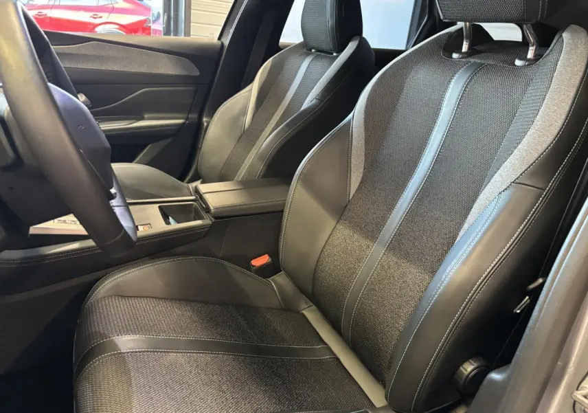 Vue intérieure rapprochée des sièges avant en sellerie tri matières noire avec surpiqûres bleues du Peugeot 308 SW gris clair.