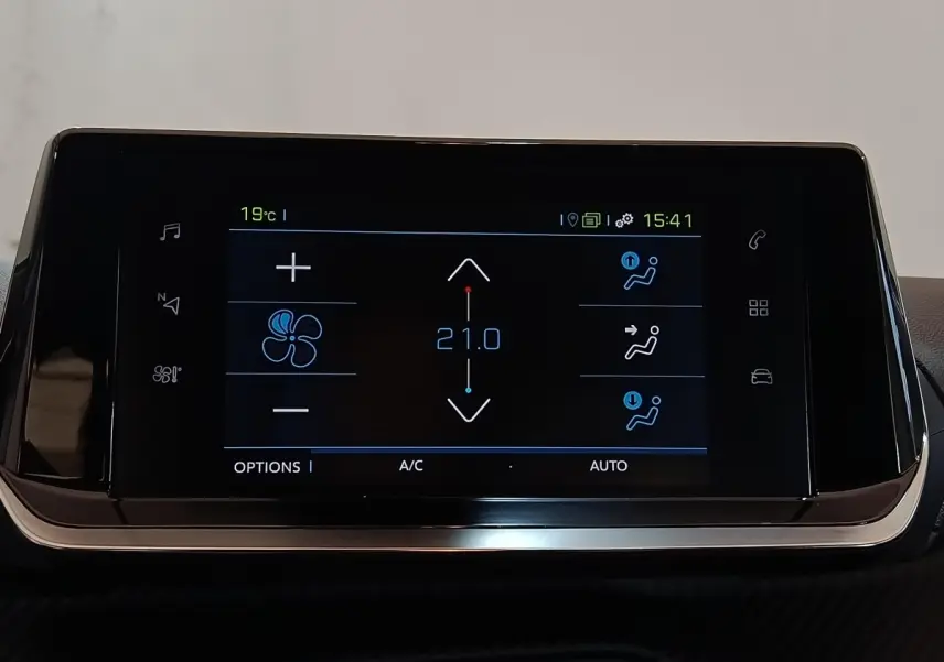 Écran tactile central noir affichant la climatisation à 21°C dans une Peugeot 208 électrique blanche.
