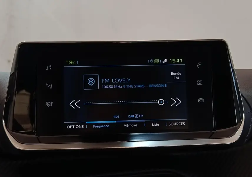 Écran tactile central de 7 pouces affichant la radio FM dans l’habitacle d’une Peugeot 208 blanche électrique.