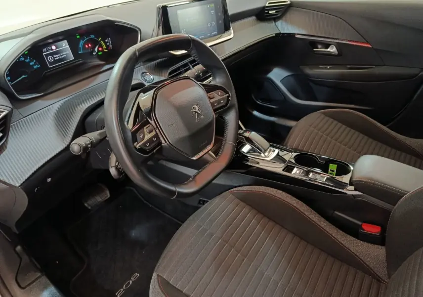 Vue intérieure côté conducteur de la Peugeot 208 électrique, tableau de bord numérique et volant cuir noir.