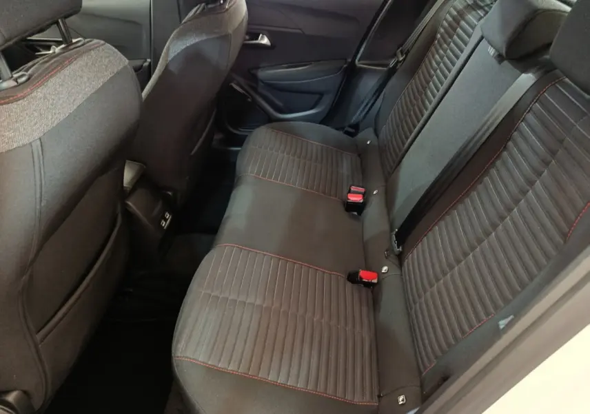 Vue côté droit de la banquette arrière noire avec surpiqûres rouges dans l’habitacle d’une Peugeot 208 blanche électrique.