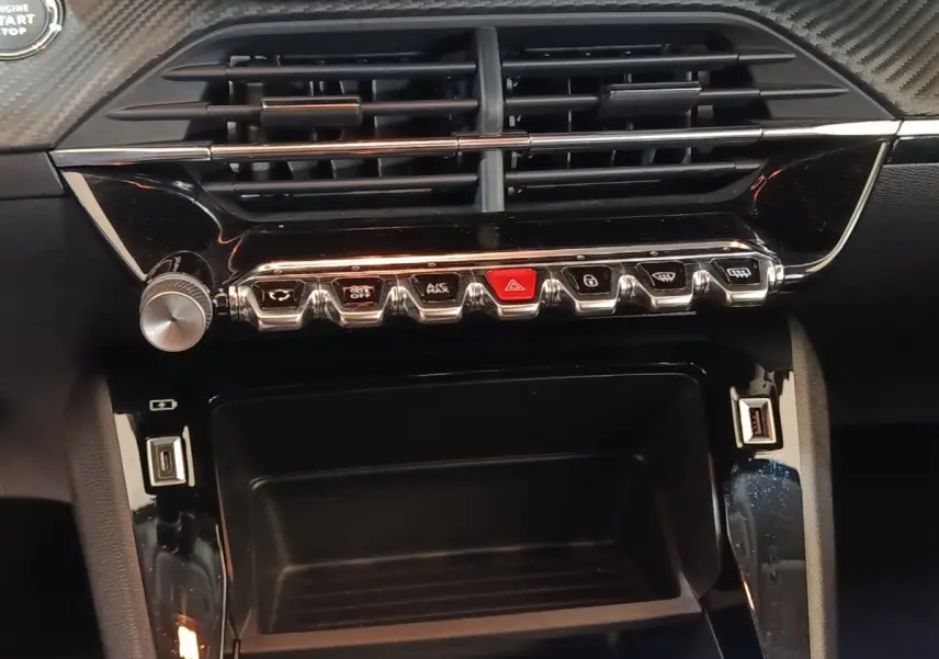 Vue rapprochée du tableau de bord noir de la Peugeot 208 électrique Active Business avec commandes et prises USB visibles.