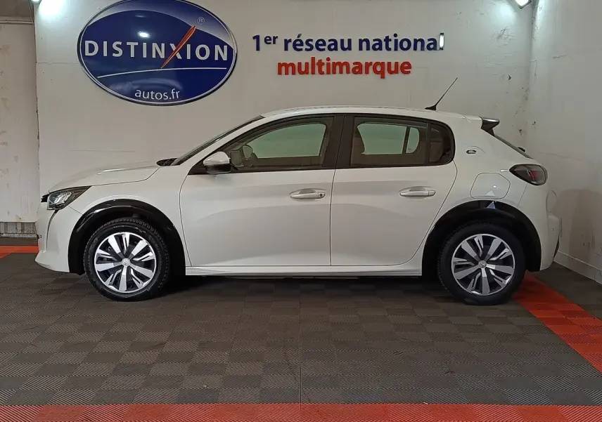 Profil latéral droit d'une Peugeot 208 Electrique Active Business blanche, stationnée en intérieur avec jantes distinctives.