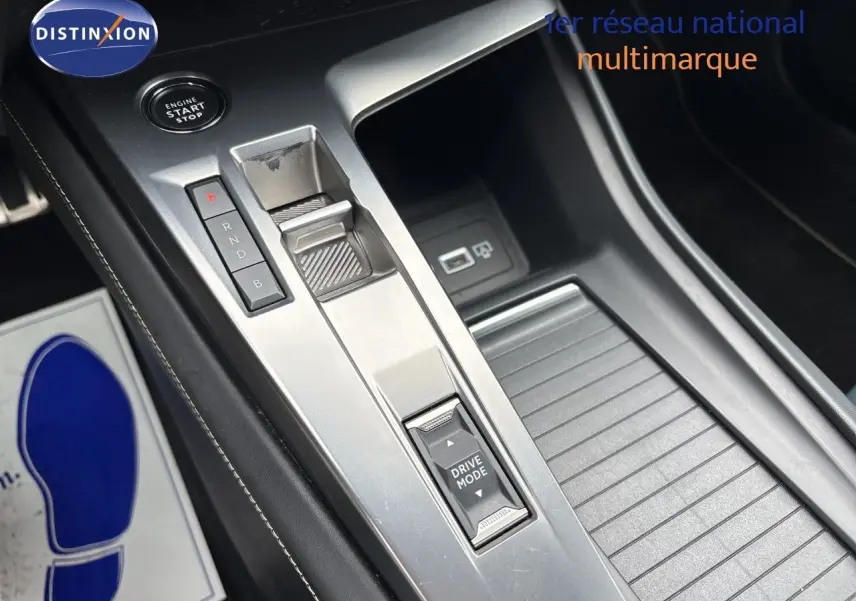 Gros plan sur la console centrale argentée de la Peugeot 308 SW hybride 2022 avec commandes de boîte auto et bouton Drive Mode.