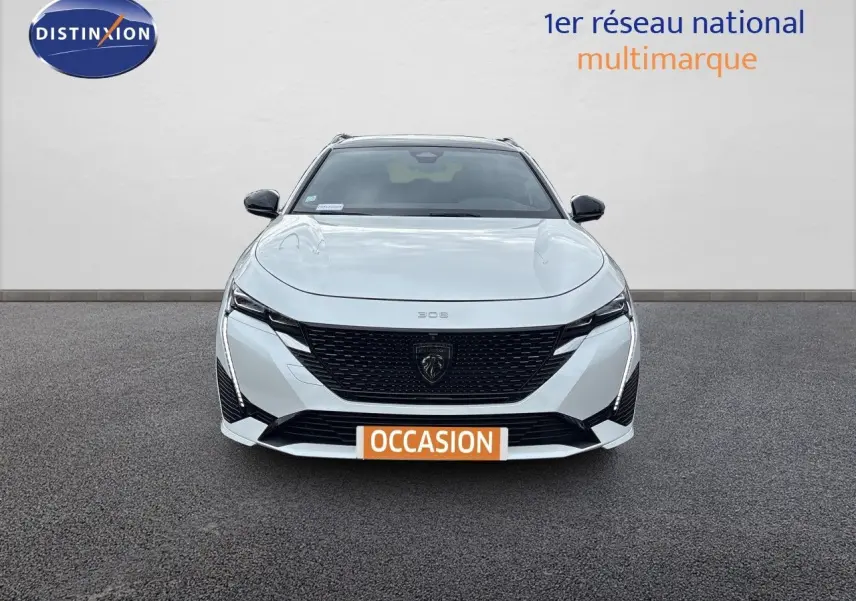 Vue frontale d'une Peugeot 308 SW hybride blanche nacrée métal avec calandre noire et phares LED distinctifs.