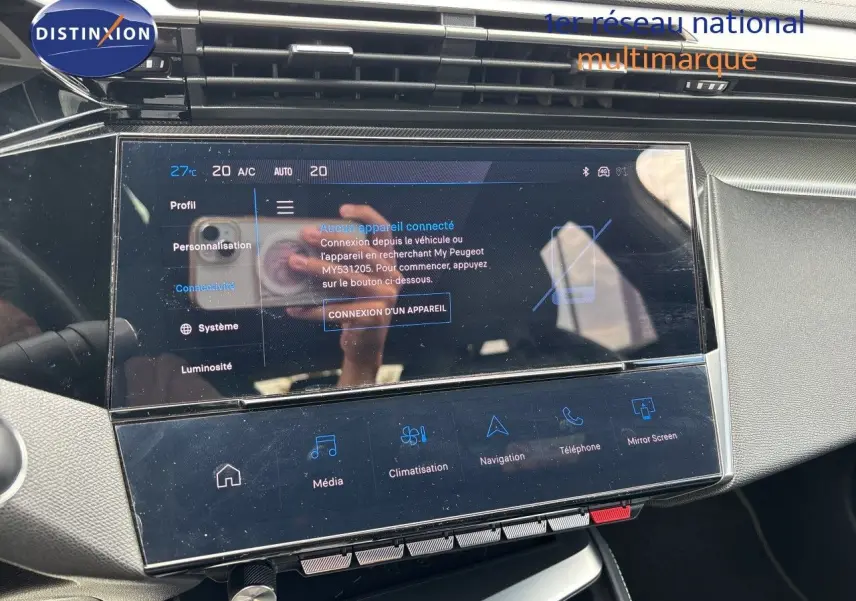 Vue rapprochée de l'écran tactile central du tableau de bord de la Peugeot 308 SW hybride blanche, affichant les options de connectivité.