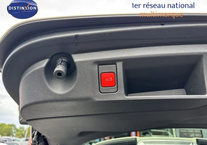 Bouton rouge d'ouverture électrique du hayon sur le bord intérieur du coffre d'une Peugeot 308 SW blanc nacré métal.