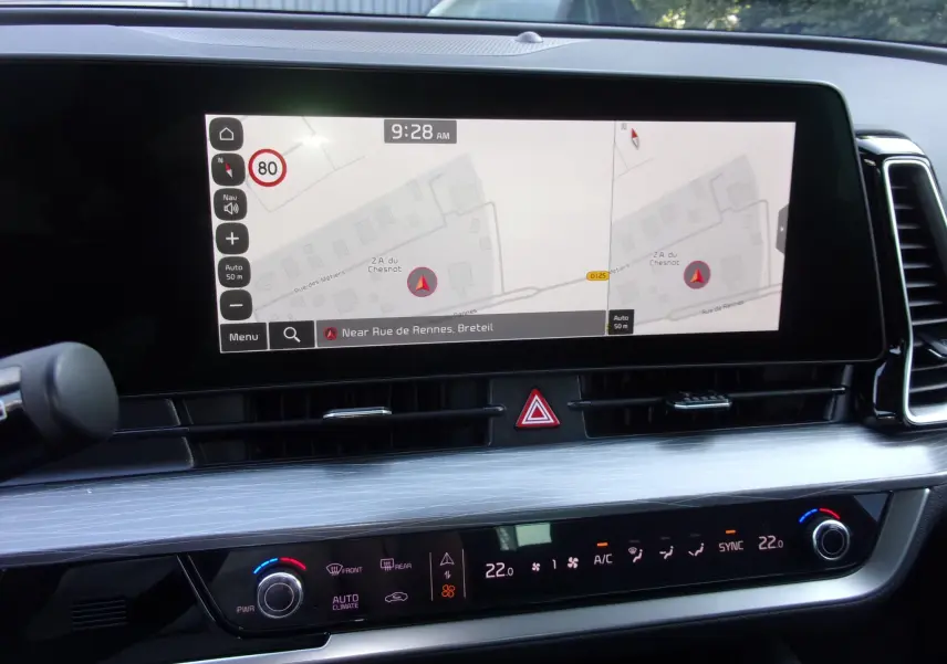 Écran tactile 12,3'' du GPS du Kia Sportage gris perle, affichant une carte et commandes de climatisation en plan rapproché.