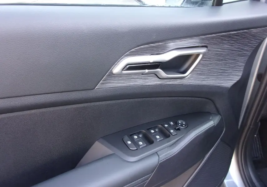 Gros plan sur la porte côté conducteur du Kia Sportage gris perle, mettant en valeur la poignée argentée et les commandes électriques.