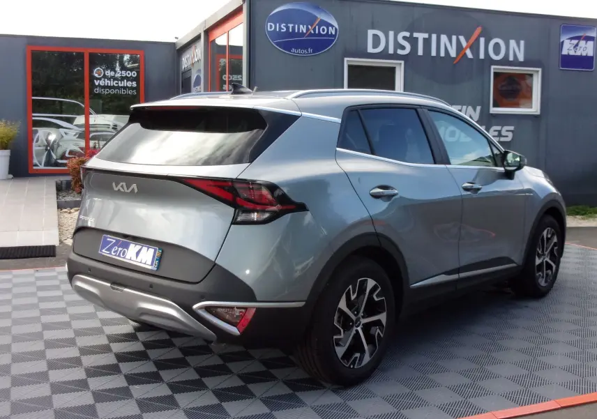 Vue 3/4 arrière droite d'un KIA SPORTAGE gris perle 2025 avec feux arrière LED et jantes alliage noires.