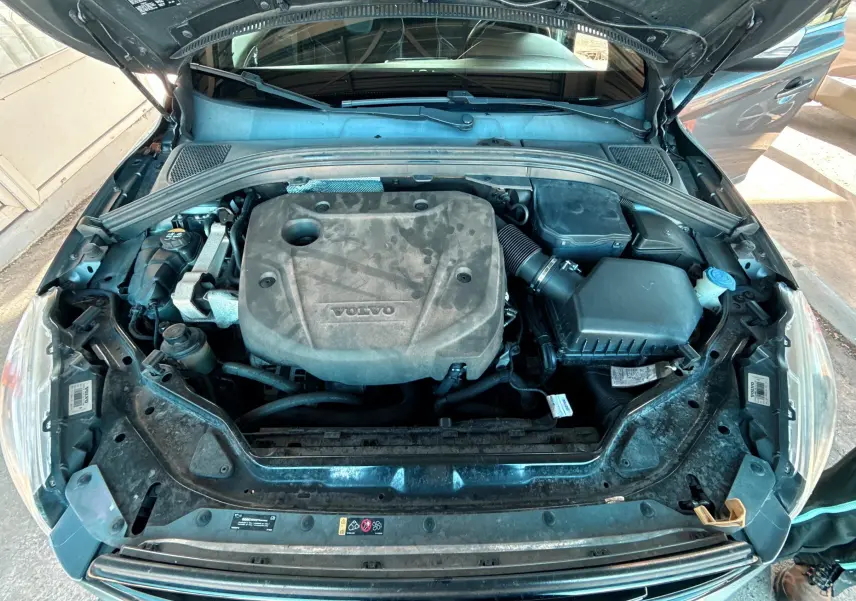Vue plongeante sur le moteur du Volvo XC60 D4 gris 2016, montrant le compartiment moteur ouvert et propre.