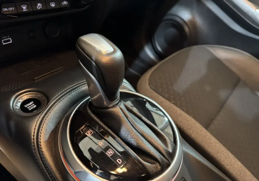 Gros plan sur le levier de vitesse automatique noir et argent du Nissan Juke gris clair, avec bouton démarrage visible.