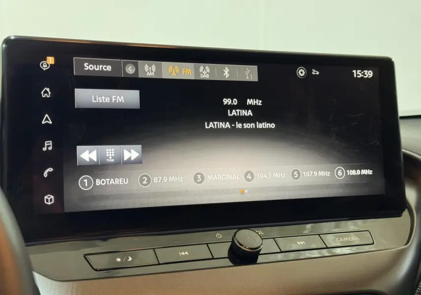 Écran tactile central affichant la radio FM dans l'habitacle du Nissan Juke gris clair, vue de face rapprochée.