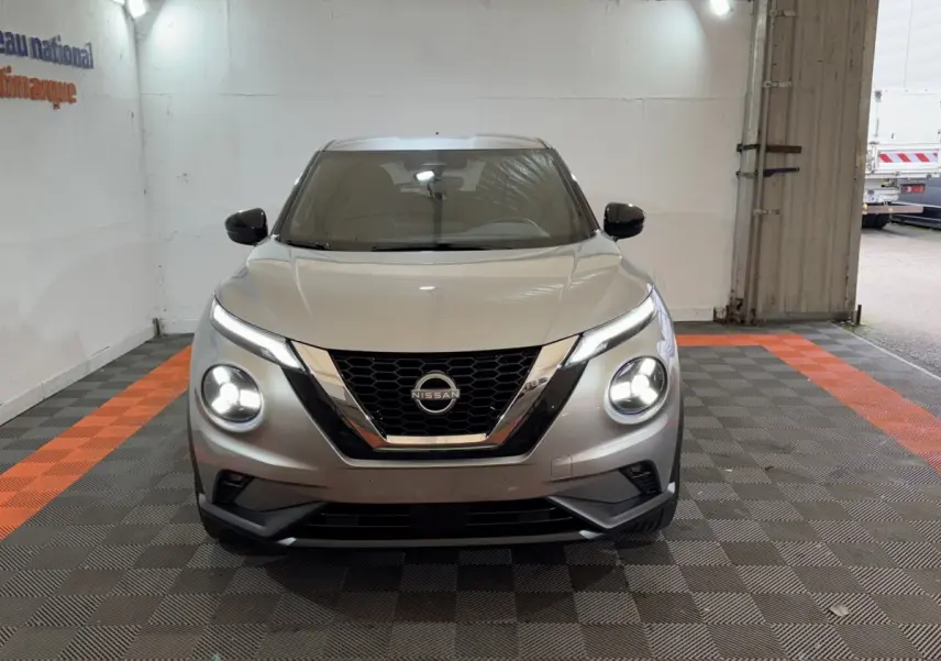 Vue frontale d'un Nissan Juke gris clair avec phares LED allumés dans un garage.