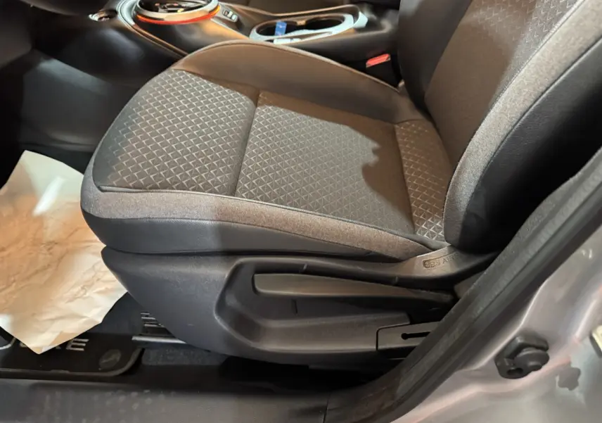 Gros plan sur le siège avant droit gris clair du Nissan Juke 2025, avec réglage manuel visible et tissu texturé.