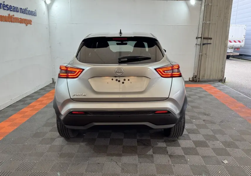 Vue arrière d'un Nissan Juke gris clair 2025 avec feux LED allumés dans un garage éclairé.