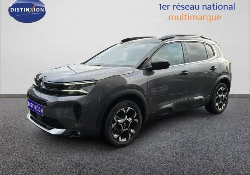 Citroën C5 Aircross Hybrid gris platinium en 3/4 avant droit avec jantes bicolores et barres de toit noires.